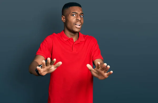 若いアフリカ系アメリカ人の男性は カジュアルな赤いTシャツを着て手で恐怖表現のジェスチャーを停止し ショックで叫んで恐れている パニックの概念 — ストック写真