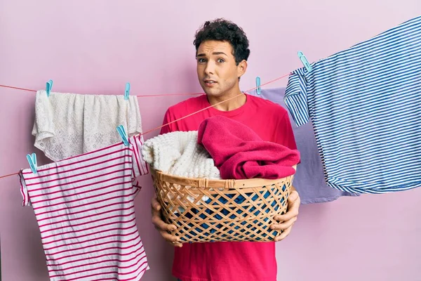 Handsome Hispanic Man Doing Laundry Holding Wicker Basket Clueless Confused — Fotografia de Stock
