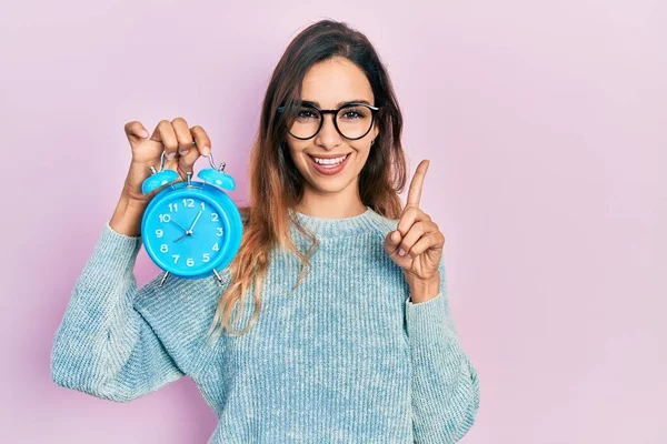 Young Hispanic Girl Holding Alarm Clock Smiling Idea Question Pointing — Stock Photo, Image