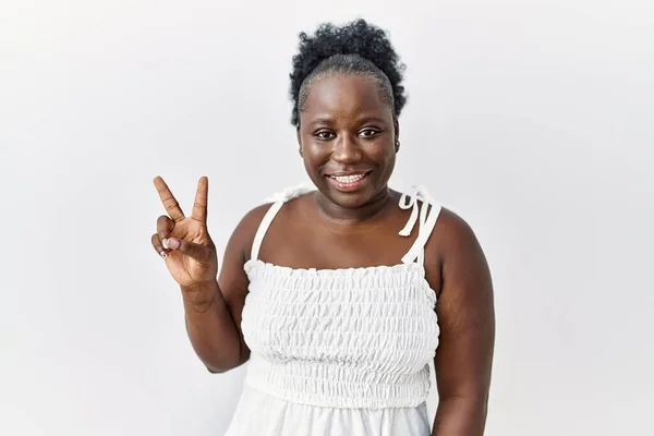 自信と幸せな笑顔ながら 白い孤立した背景に立っている若いアフリカの女性は指の数2で示すと指摘します — ストック写真