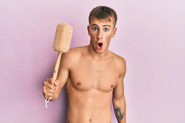 Young Caucasian Man Shirtless Holding Shower Sponge Scared Amazed Open — Zdjęcie stockowe