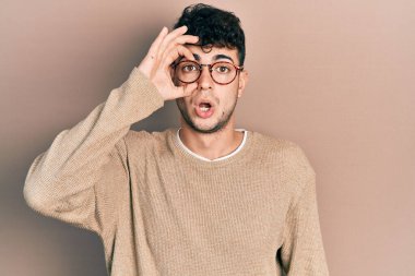Günlük kıyafetler ve gözlük takan genç İspanyol adam şaşırmış yüz ifadesiyle şaşırmış, parmaklarından bakan gözler. İnançsız ifade. 