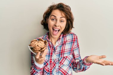 Çikolata parçalı kurabiyeler taşıyan genç esmer kadın başarıyı mutlu bir gülümsemeyle ve kazanan yüz ifadesiyle kutluyor. 