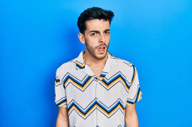 Şok olmuş gibi giyinen genç İspanyol adam şüpheci ve alaycı görünüyor, ağzı açık kalınca şaşırıyor. 