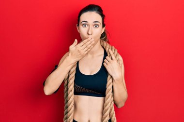 Savaş halatıyla eğitilmiş, ağzı elle kapatılmış, şok olmuş ve hata yapmaktan korkan genç bir İspanyol kız. şaşırmış ifade 