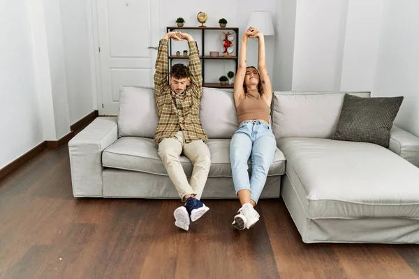 Young Hispanic Couple Relaxed Stretching Arms Sitting Sofa Home — Fotografia de Stock