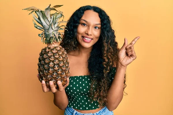 Young Latin Woman Holding Pineapple Smiling Happy Pointing Hand Finger — Fotografia de Stock