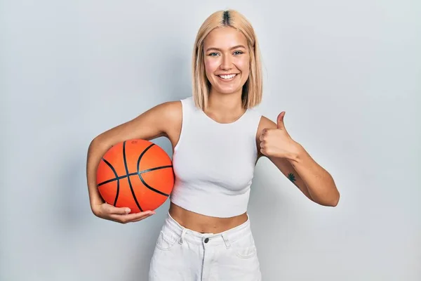 美しいブロンド女性保持バスケットボールボール笑顔と正 親指アップ行う優れた承認サイン — ストック写真
