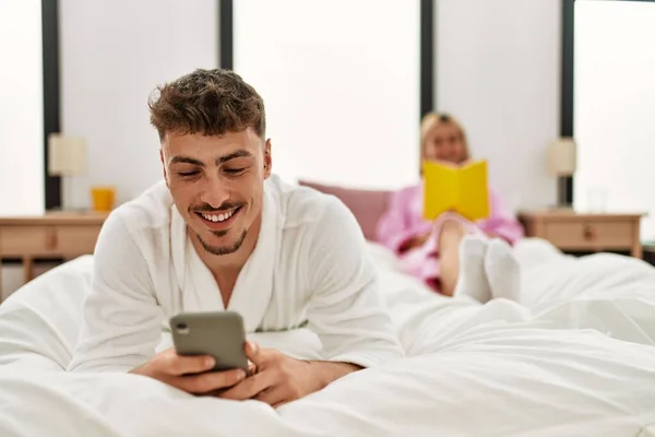 Genç Beyaz Çift Kitap Okuyor Yatak Odasında Akıllı Telefon Kullanıyor — Stok fotoğraf