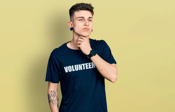 Young caucasian boy with ears dilation wearing volunteer t shirt touching painful neck, sore throat for flu, clod and infection