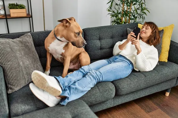 Jovem Caucasiana Usando Smartphone Deitado Sofá Com Cão Casa — Fotografia de Stock