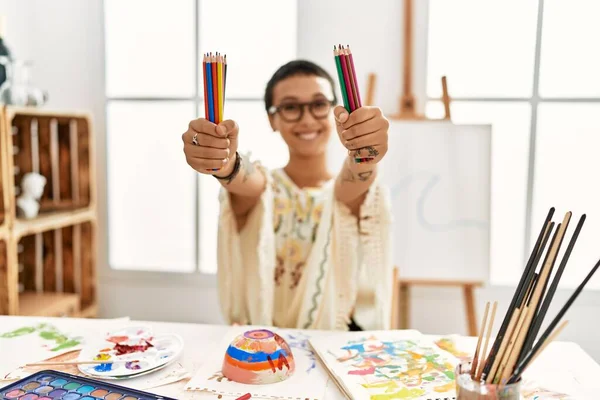 年轻的惊慌失措的女人带着自信的笑容在艺术工作室里拿着彩笔 — 图库照片