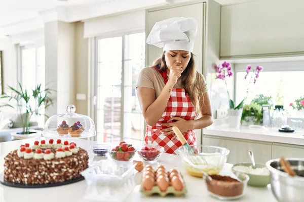 Güzel, genç, esmer pasta şefi kadın mutfakta hamur işi pişirirken kendini iyi hissetmiyor ve soğuk algınlığı veya bronşitin belirtisi olarak öksürüyor. sağlık hizmeti kavramı. 