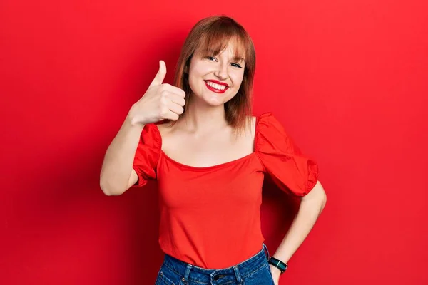 Kırmızı Tişörtlü Kızıl Saçlı Genç Bir Kadın Mutlu Baş Parmaklarıyla — Stok fotoğraf