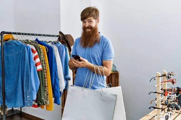 Jonge Roodharige Klant Met Boodschappentassen Smartphone Kledingwinkel — Stockfoto