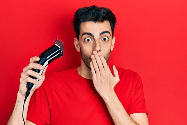 Young Hispanic Man Charging Electric Razor Machine Covering Mouth Hand — Stock Photo, Image