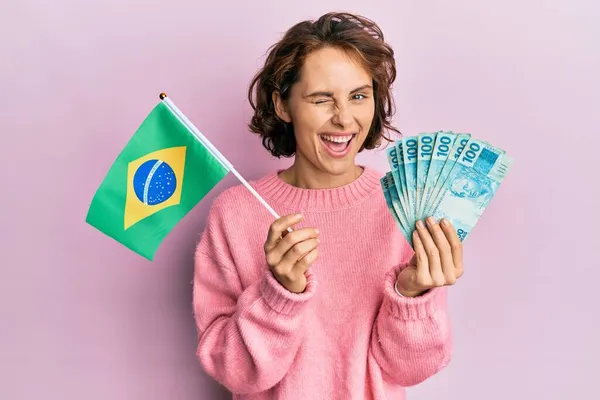 Mladá Brunetka Žena Drží Brazilskou Vlajku Skutečné Bankovky Mrkání Fotoaparát — Stock fotografie