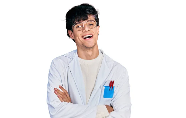 カメラを見ながら腕を交差させて笑顔で医者の制服を着たハンサムなヒップスターの若者 正の人 — ストック写真