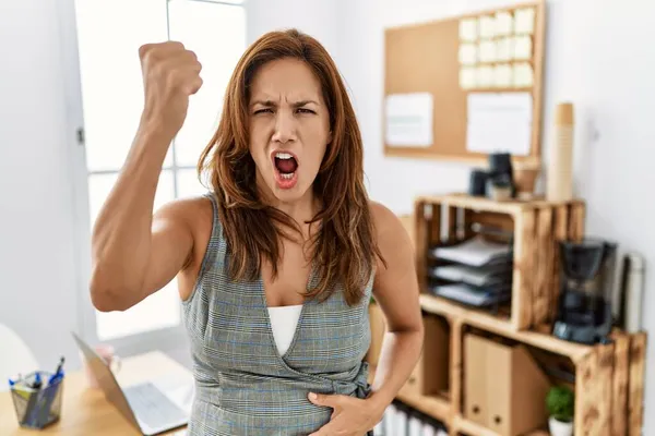 中年时 办公室里惊慌失措的女人怒气冲冲地举起拳头 怒气冲冲地大喊大叫 愤怒和好斗的概念 — 图库照片