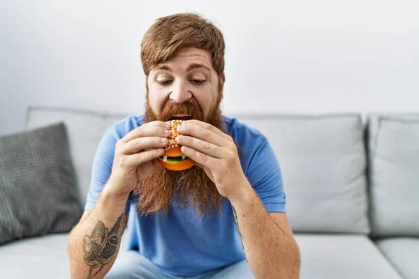 Giovane Irlandese Uomo Sorridente Felice Mangiare Hamburger Classico Seduto Sul — Foto Stock