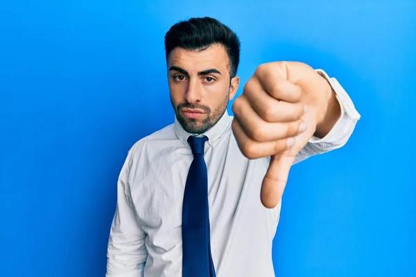 ビジネス服を着た若いヒスパニック系の男は 親指を下にジェスチャーで拒絶と否定を示す不満と怒りを見ています 悪い表現 — ストック写真