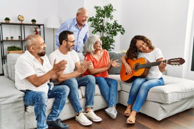 Bir grup orta yaşlı arkadaş evdeki kanepede oturup klasik gitar çalıyorlar..