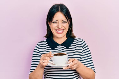 Genç İspanyol kadın bir fincan kahve içiyor ve kahkahalarla gülüyor.. 