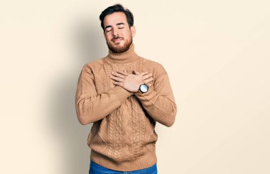 Gündelik kıyafetler giyen genç İspanyol adam elleri göğsünde, gözleri kapalı ve yüzünde minnet dolu bir jest ile gülümsüyor. sağlık kavramı. 