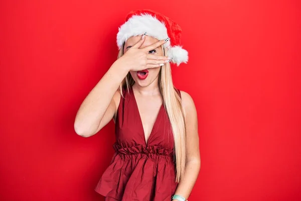 Mladá Blondýnka Vánočním Klobouku Vykukuje Šoku Zakrývá Obličej Oči Rukou — Stock fotografie