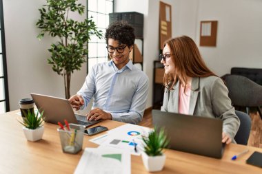 Ofiste dizüstü bilgisayarla çalışırken gülümseyen iki iş adamı..