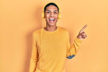 Genç Afro-Amerikalı adam müzik dinliyor. Kulaklık takıyor. Yüzünde kocaman bir gülümseme var.. 