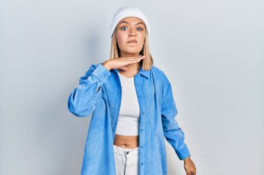 Güzel sarışın kadın yün şapka takıyor. Bıçak niyetine boğazını kesiyor. Saldırganlığı şiddetle tehdit ediyor. 