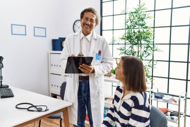 Doktor üniforması giyen orta yaşlı bir adam ve kadın klinikte tıbbi danışmanlık yapıyorlar.