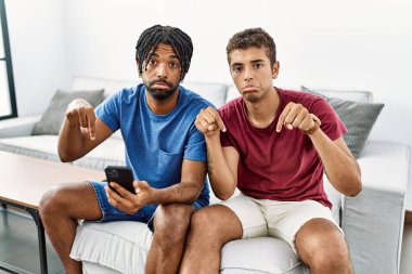 Evdeki koltukta oturan İspanyol asıllı genç adamlar üzgün ve üzgün görünüyor, parmaklarıyla yön gösteriyor, mutsuz ve depresif.. 