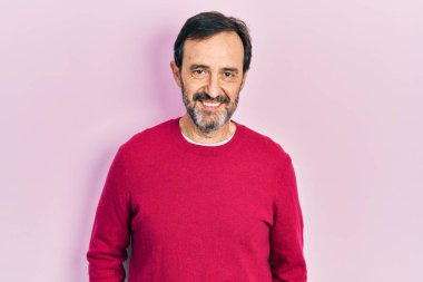 Orta yaşlı İspanyol bir adam mutlu ve havalı bir gülüşü olan sıradan kıyafetler giyiyor. şanslı kişi. 