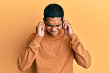 Gürültülü müzik sesi için günlük kazak giyen genç, yakışıklı İspanyol adam kulaklarını parmaklarıyla kapatıyor. sağır kavramı. 