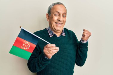 Gri saçlı yakışıklı son sınıf öğrencisi elinde Afganistan bayrağı ile gururla bağırıyor, zaferi ve başarıyı kutluyor. 