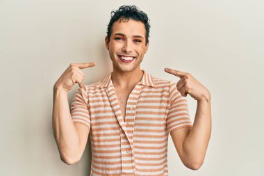 Handsome man wearing make up wearing casual t shirt smiling cheerful showing and pointing with fingers teeth and mouth. dental health concept. 