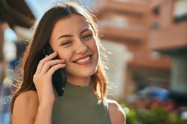 Beyaz kız gülümsüyor. Şehirdeki akıllı telefondan konuşuyor..