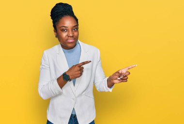 Genç Afro-Amerikan kadın iş kıyafetleri içinde endişeli ve gergin bir şekilde iki elini de işaret ederek endişeli ve şaşırmış bir ifade takındı. 