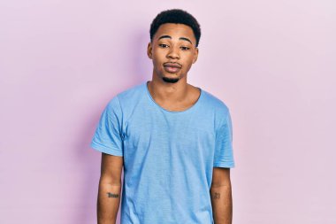 Young african american man wearing casual blue t shirt relaxed with serious expression on face. simple and natural looking at the camera. 