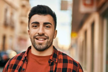 Genç İspanyol adam gülümseyerek şehirde mutlu mesut dikiliyor..