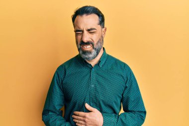 Orta yaşlı, sakallı, gri saçlı, eli karnında iş kıyafetleri giyen bir adam. Çünkü mide bulantısı, acı verici bir hastalık kendini iyi hissetmiyor. Ağrı kavramı. 