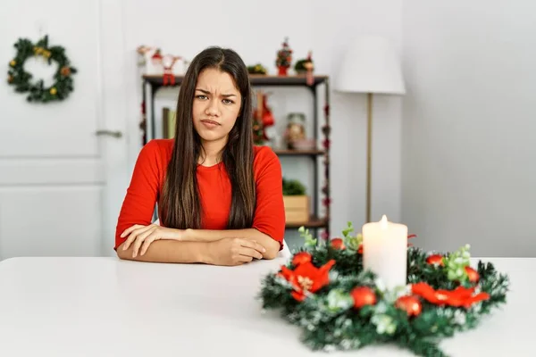 Jovem Morena Sentada Mesa Natal Cética Nervosa Desaprovando Expressão Rosto — Fotografia de Stock