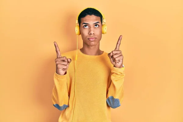 Young African American Guy Listening Music Using Headphones Pointing Looking — 图库照片