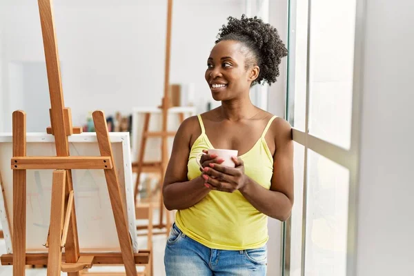 若いアフリカ系アメリカ人アーティストの女性がアートスタジオでコーヒーを飲む — ストック写真