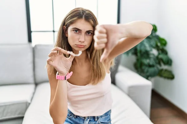 Young Blonde Woman Holding Invisible Aligner Orthodontic Looking Unhappy Angry — стоковое фото