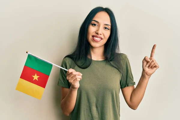 Mladá Hispánka Drží Kamerunskou Vlajku Šťastně Úsměvem Ukazuje Rukou Prstem — Stock fotografie
