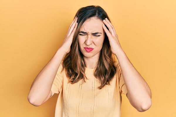 Young hispanic girl wearing casual clothes suffering from headache desperate and stressed because pain and migraine. hands on head. 
