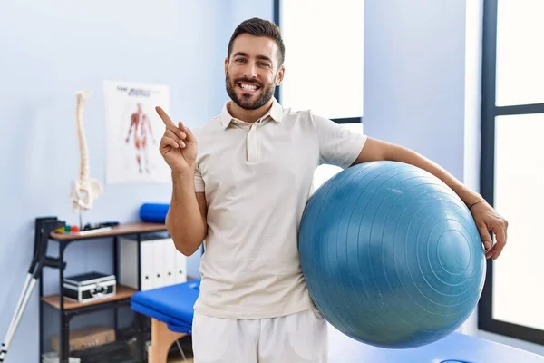 Handsome Hispanic Man Holding Pilates Ball Rehabilitation Clinic Smiling Happy — Foto de Stock